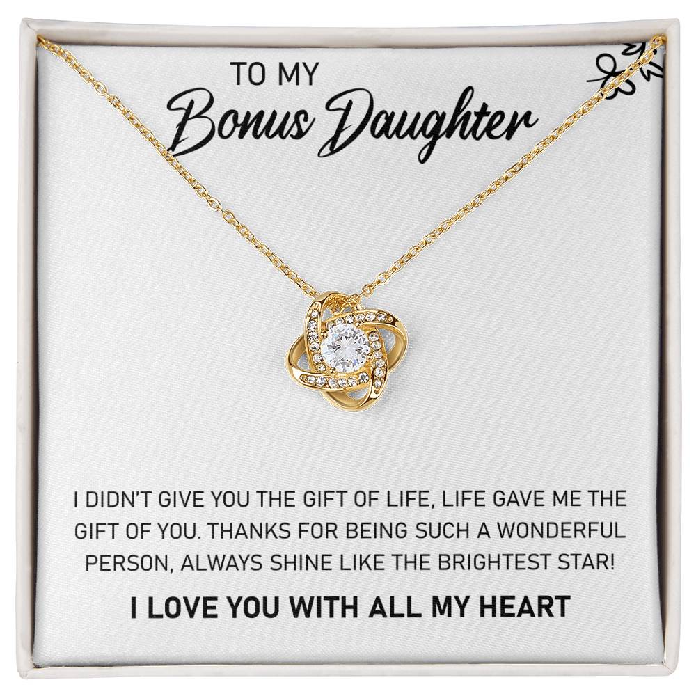 Yellow Gold Love Knot Necklace with Large CZ crystal in center, urrounded by smaller crystals. Shown in Standard Gift Box. Message card reads: To My Bonus Daughter: I didn't give you the gift of life, life gave me the gift of you. Thanks fo rbeing such a wonderful person, always shine like the brightest star. I love you with all my heart.
