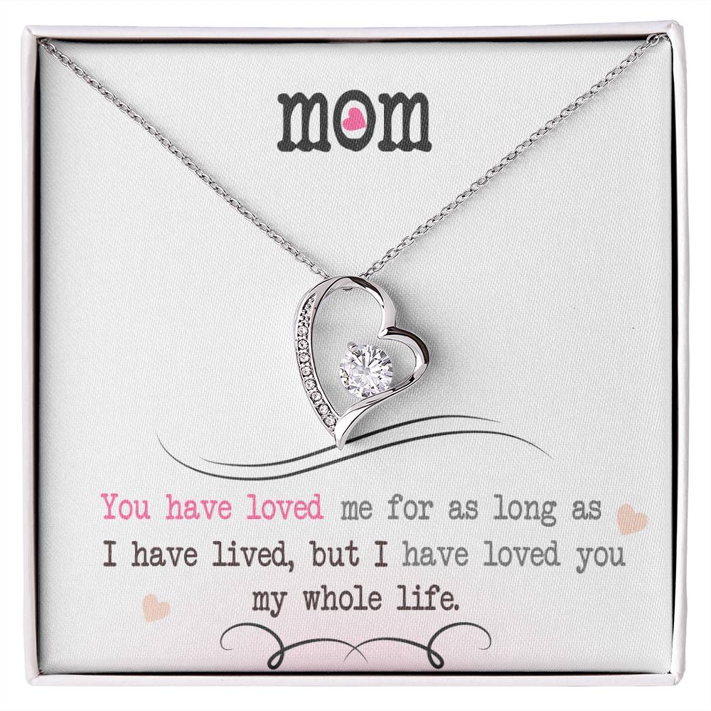 Silver heart necklace with cubic zirconia in the center and several smaller stones on one side. Shown in standard gift box. Message reads: Mom You have loved me for as long as I have lived, but I have loved you my whole life.