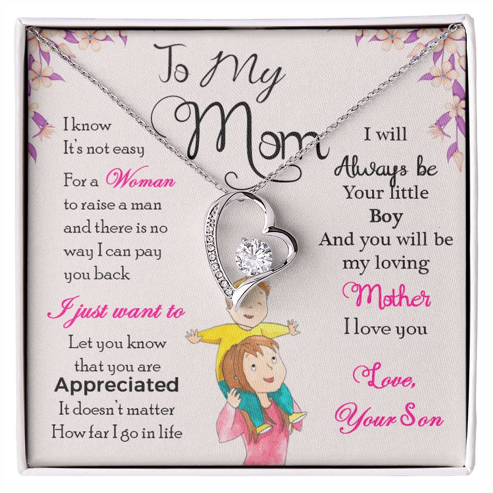 White Gold Heart Necklace with Cubic Zirconia in Center and small stones on one side of the heart. Black Gift Box. Message card behind it shows a mom with a little boy on her shoulders. Card reads: To My Mom: I know it's not easy for a woman to raise a man and there is no way I can pay you back. I just want you to know that you are appreciated. It doesn't matter how far I go in life I will always be your little boy and you will always be my loving mother. I love you. Love, your son. - Givethegifts.com
