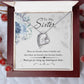 White Gold Forever Love Heart Necklace. Large CZ crystal at center with small crystals along one side. Shown in Luxury Gift Box. Message reads:To My Sister: There are friends, there is family, and then there are friends who become family... thank you for being my unbiological sister. There are blue flowers in the background.