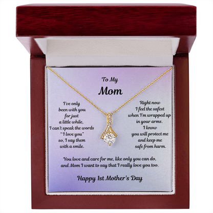 Yellow Gold Alluring Beauty Necklace Drop Pendant Style with a Large CZ crystal in center and small crystals accenting. Message reads: To My Mom: I've only been with you for just a little while, I can't speak the words "I love you" so I say them with a smile. Right now I feel the safest when I'm wrapped up in your arms. I know you will protect me and keep m safe from harm. You love and care for me, like only you can do, and Mom I want to say that I really love you too. Happy 1st Mother's Day.