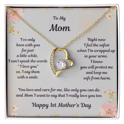 Yellow Gold Forever Love Heart Necklace with large CZ crystal at center and smaller crystals along one side. Message reads: To My Mom: I've only been with you for just a little while, I can't speak the words " I love you" so I say them with a smile. Right now I feel the safest when 'm wrapped up in your arms. I know you will protect me and keep me safe from harm. You love and care for me, like only you can do, and Mom I want to say that I really love you too. Happy 1st Mother's Day. Givethegifts.com